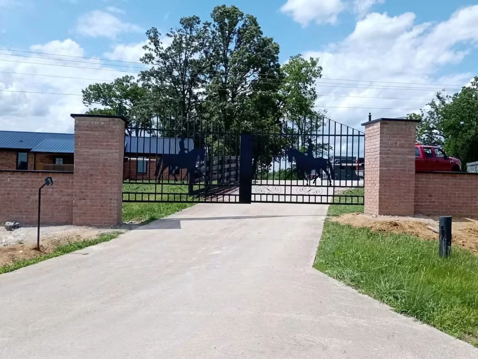 Custom black estate gate installed between brick columns